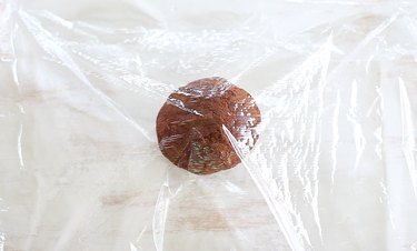 Ball of dough placed between plastic wrap